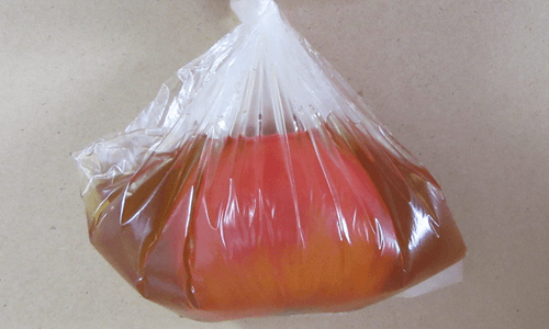 ポリ袋の中で出汁に浸されたトマトの画像